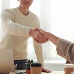 Gros plan de professionnels se serrant la main autour d'un café dans un bureau moderne.